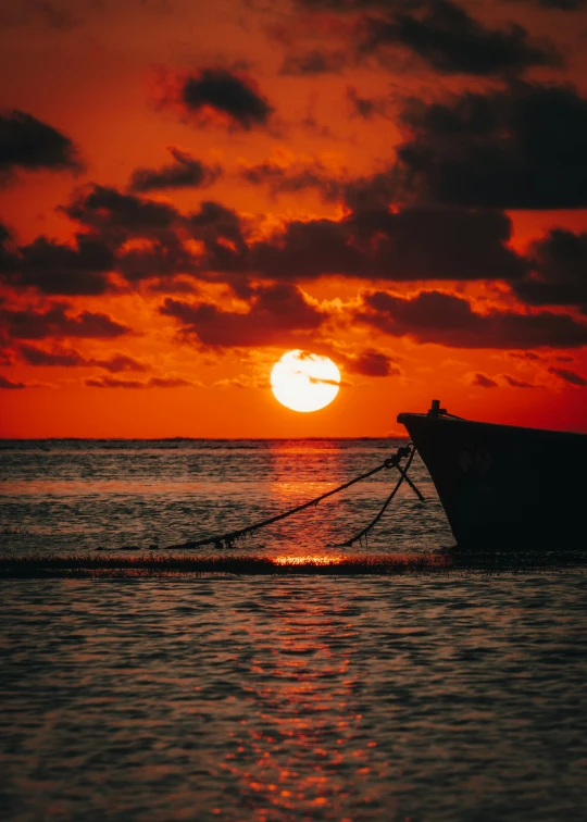 the sun is setting over a boat sitting on the water