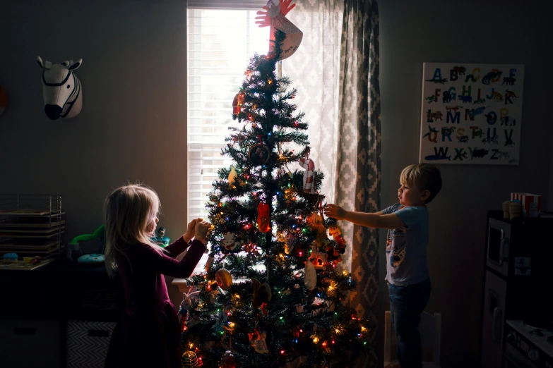 there are children standing next to the christmas tree