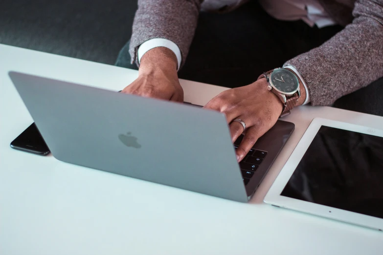 a person typing on their laptop in front of two pictures of themselves