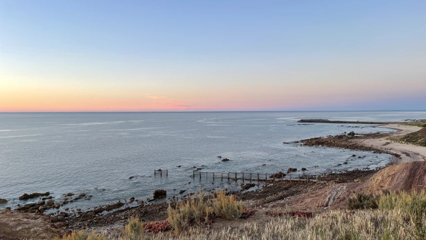 a sunset over the ocean and water near a fence