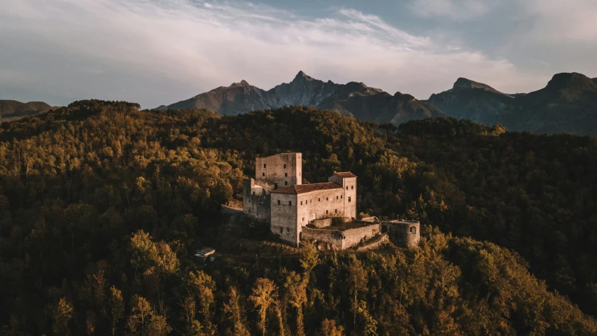 an old castle on a hill with mountains in the background