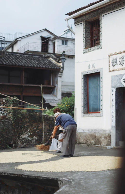 a person using a broom to clean concrete on a street