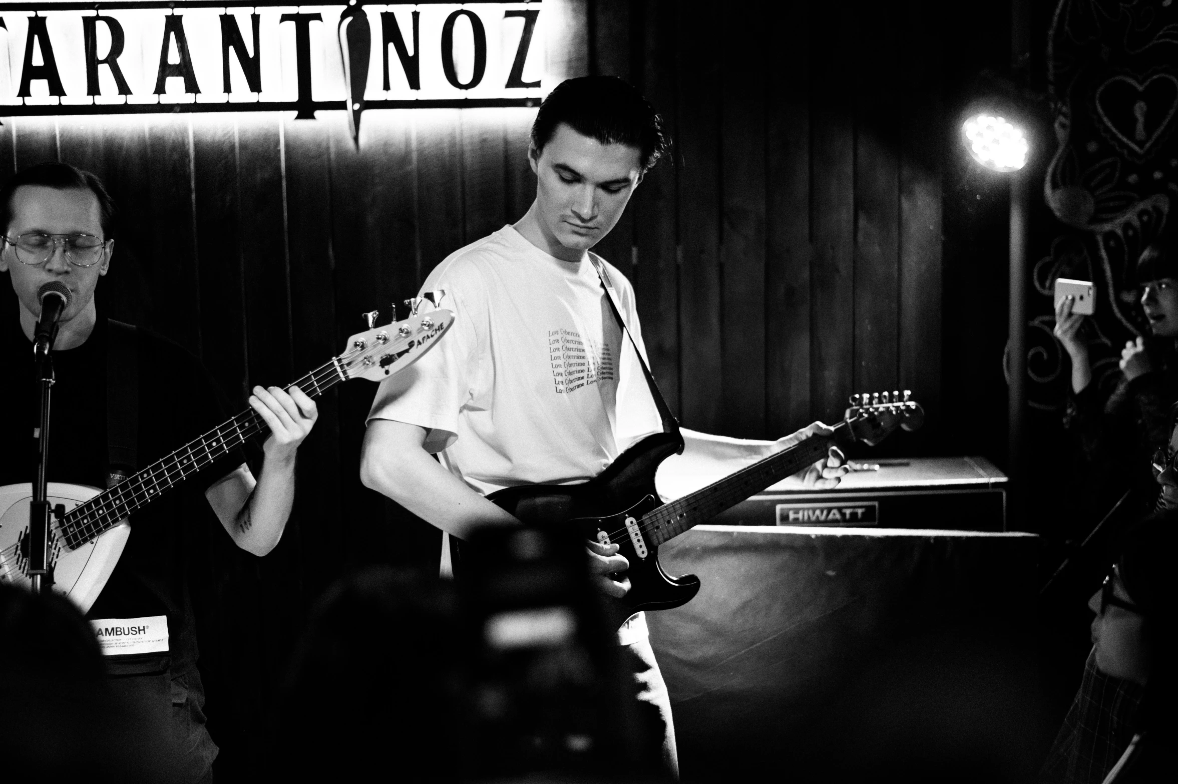 two men standing on stage playing guitar in front of a band