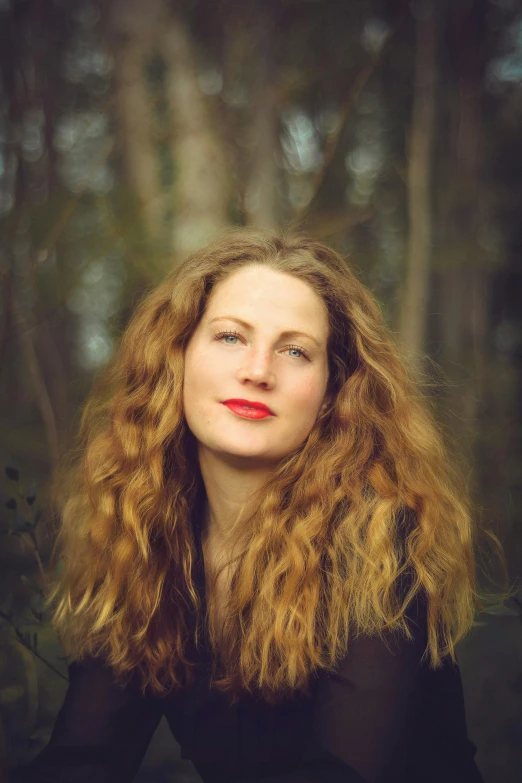 a woman standing in front of trees with long hair