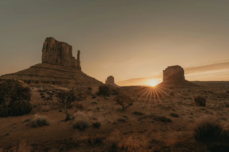 the sun rises on two rock formations in desert