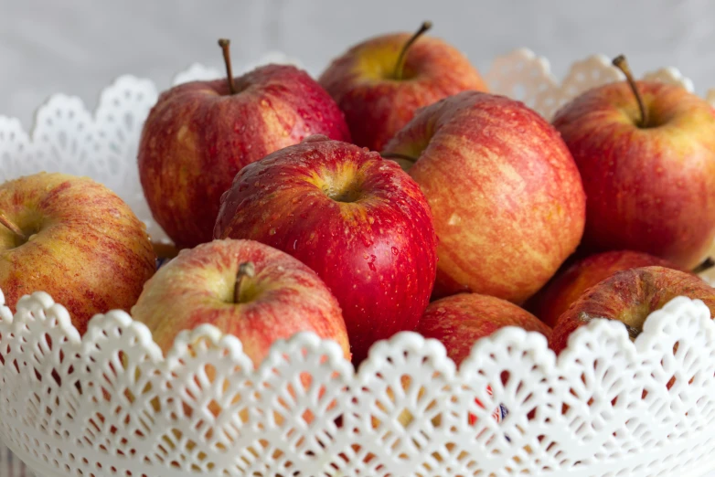 a group of red apples inside a white basket