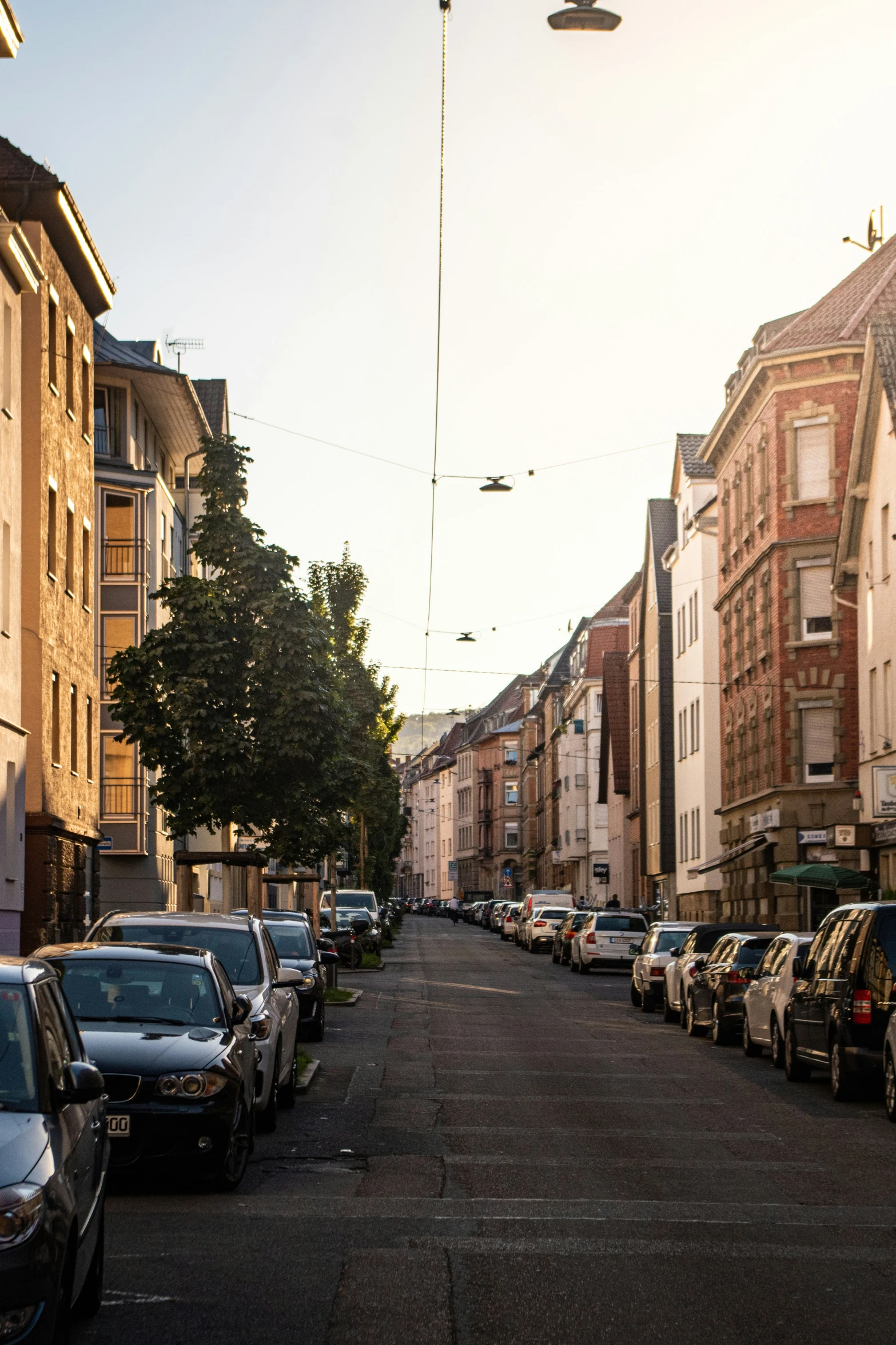 a street lined with parked cars next to tall brown buildings