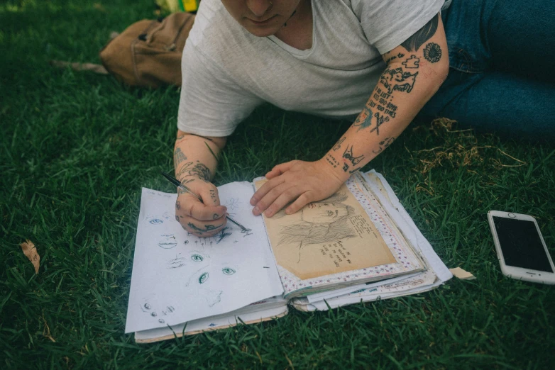 a person that is sitting in the grass writing