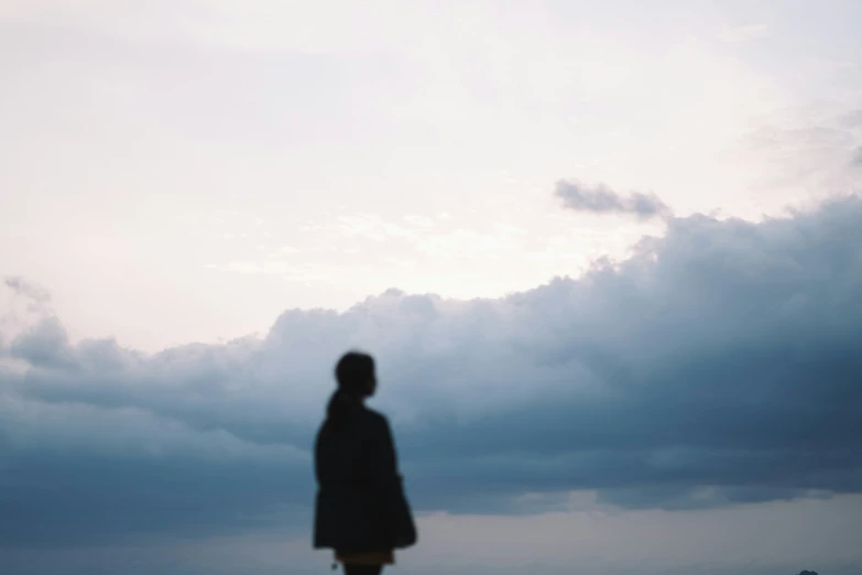 the girl is looking into the clouds as she stands