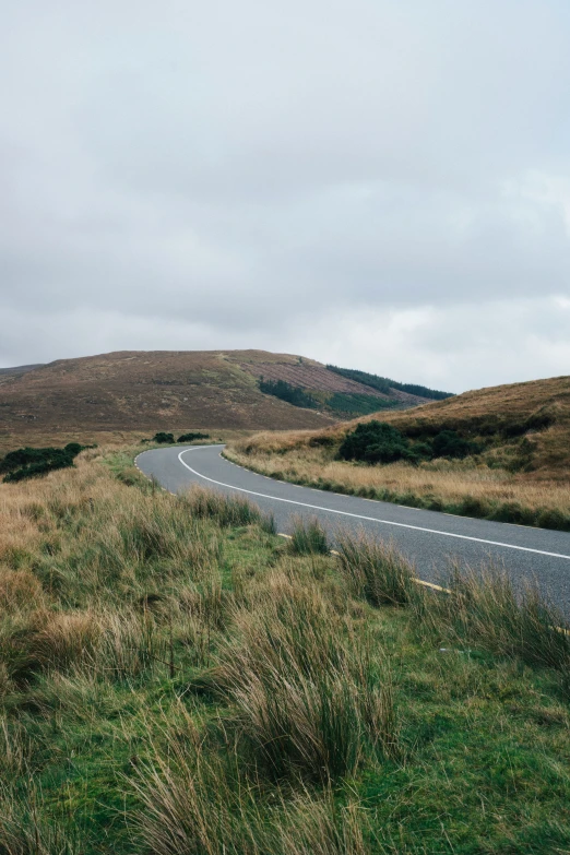 a winding road in the middle of some grassy hills