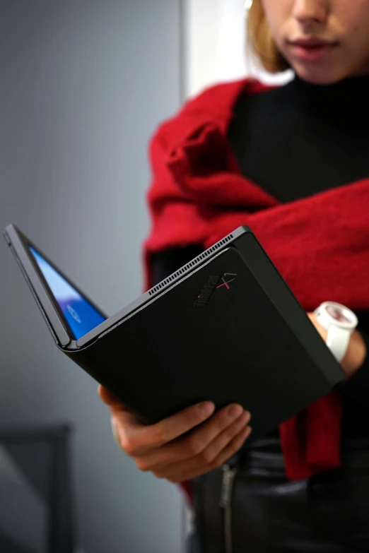 a woman holding a book and an open laptop