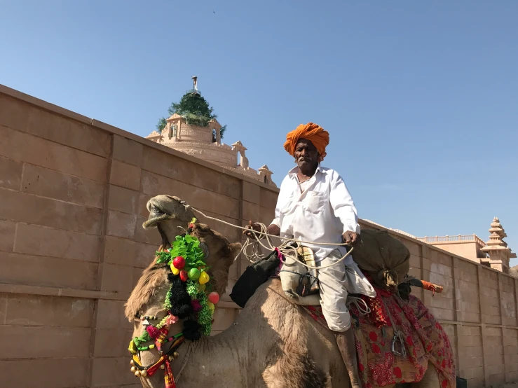 a man riding a camel next to a brown wall