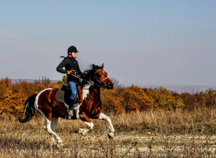 the young man is horseback riding through the field