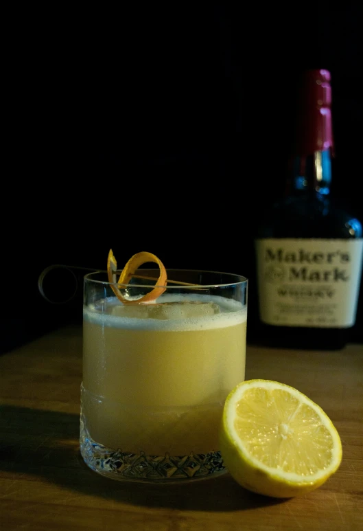 a drink sitting on top of a wooden table next to a bottle