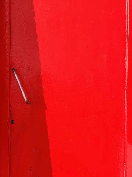 the door is painted red and the handle on the wall has a black stripe