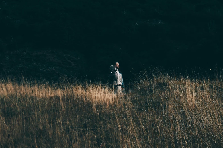 a man walking through a grass covered field