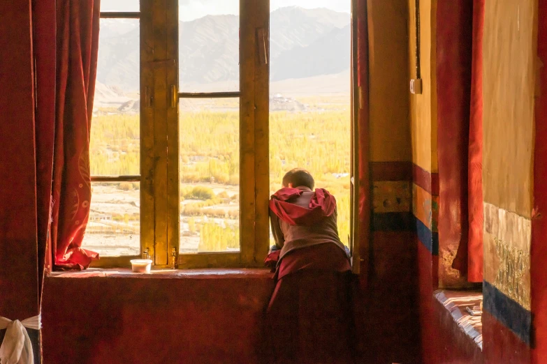 a woman sits by a window looking out