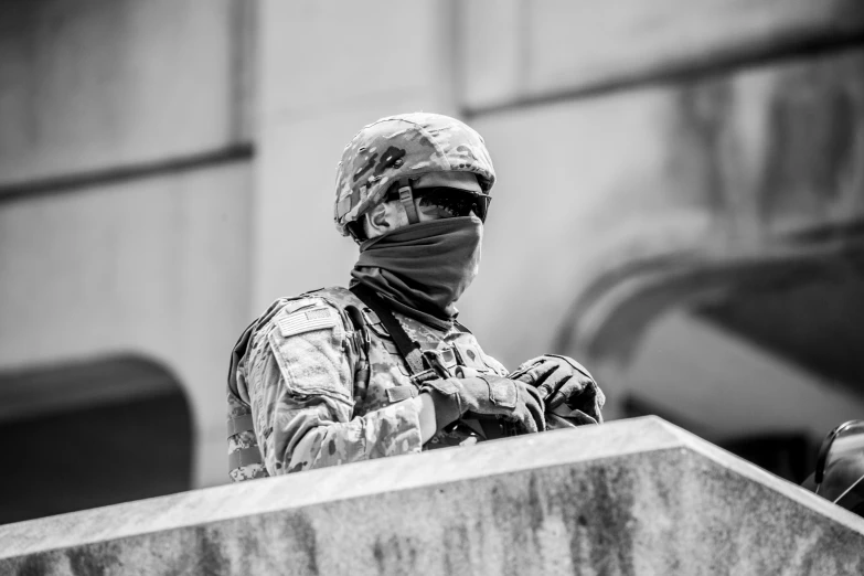 a man in military clothing wearing a face mask standing behind a large stone podium