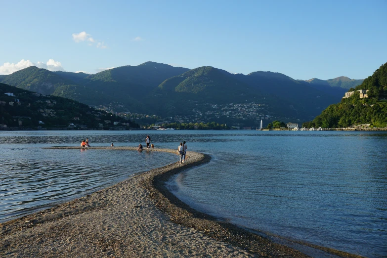 people walking on rocks next to a large body of water