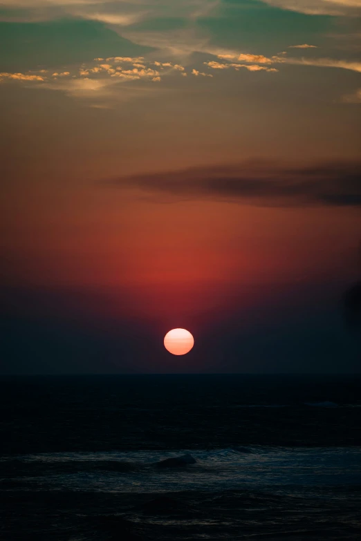 a bright sunset over the ocean as a large orange sun rises