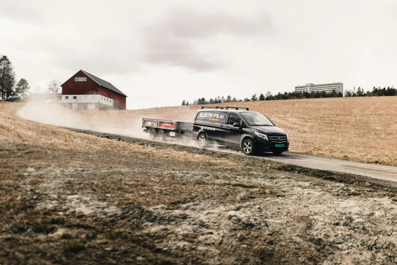 a pickup truck driving through some farm fields on a cloudy day