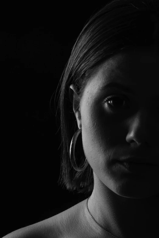 a young woman with dark makeup and a very short hair looks off to the side