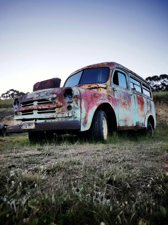 an old rusty truck sits in a grassy field