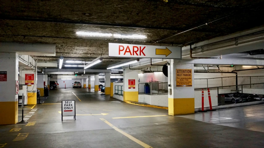 a long parking garage with a few red and white signs