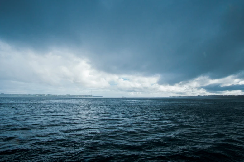 dark sky and ocean waters with green island in background