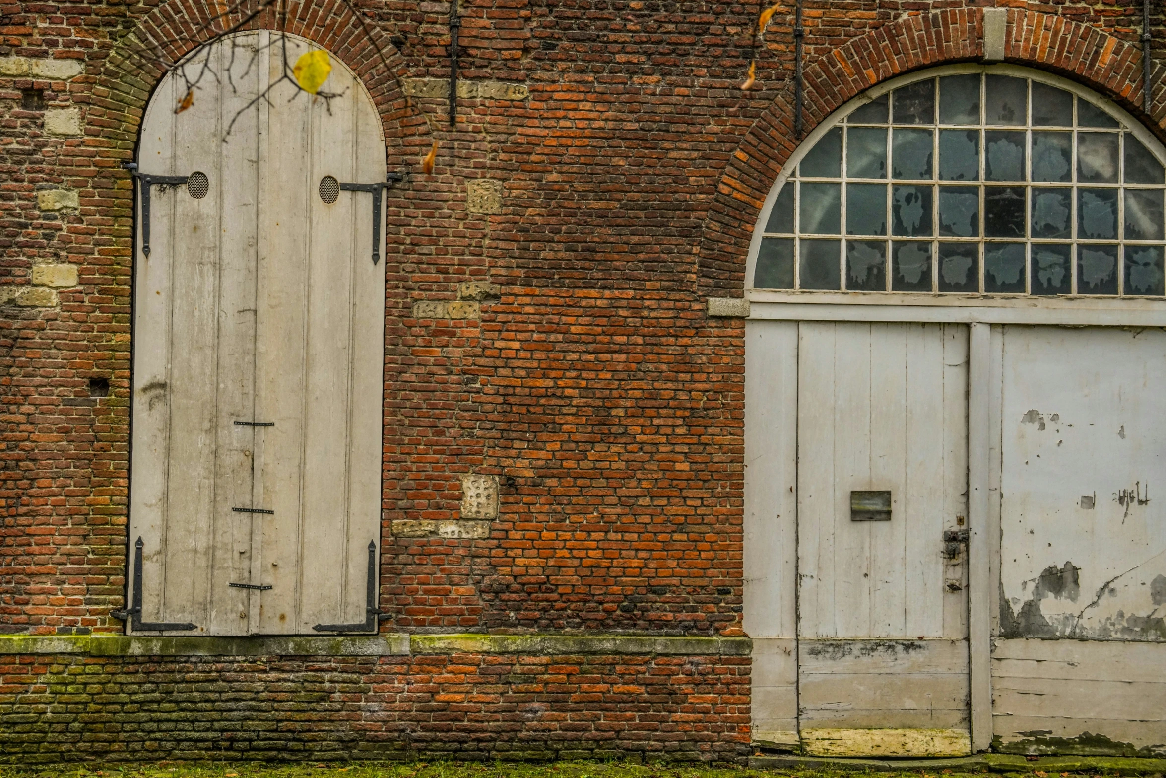 the doors are closed and they have a small window in the brick wall