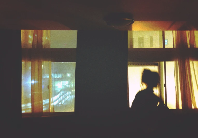 a woman looks out a window at the light coming through