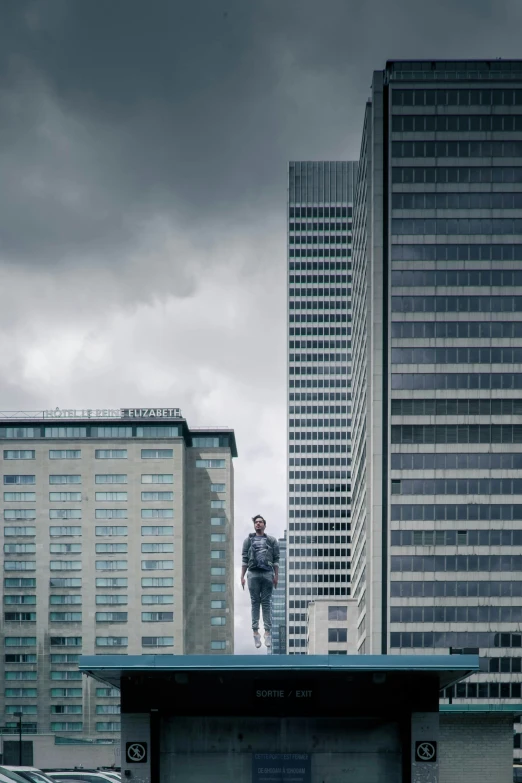 man standing on roof with two other skyscrs in background