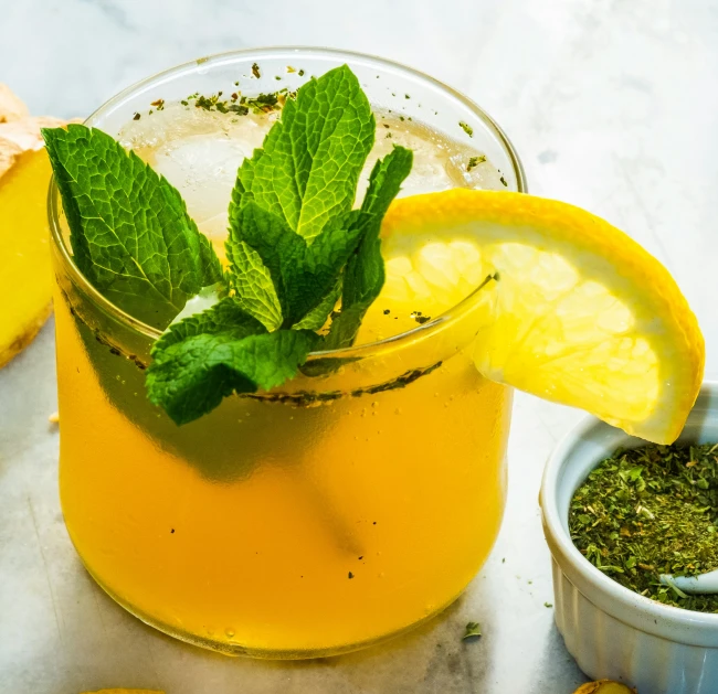 a glass with lime mint and lemon slices next to it