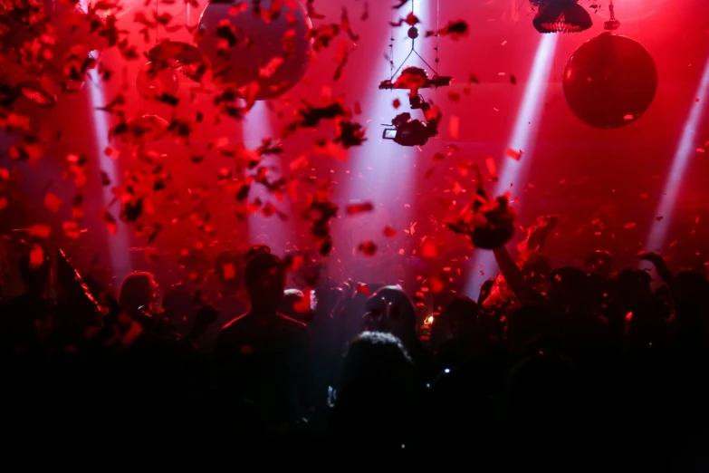 a crowd of people are performing in front of a stage with red and white lights