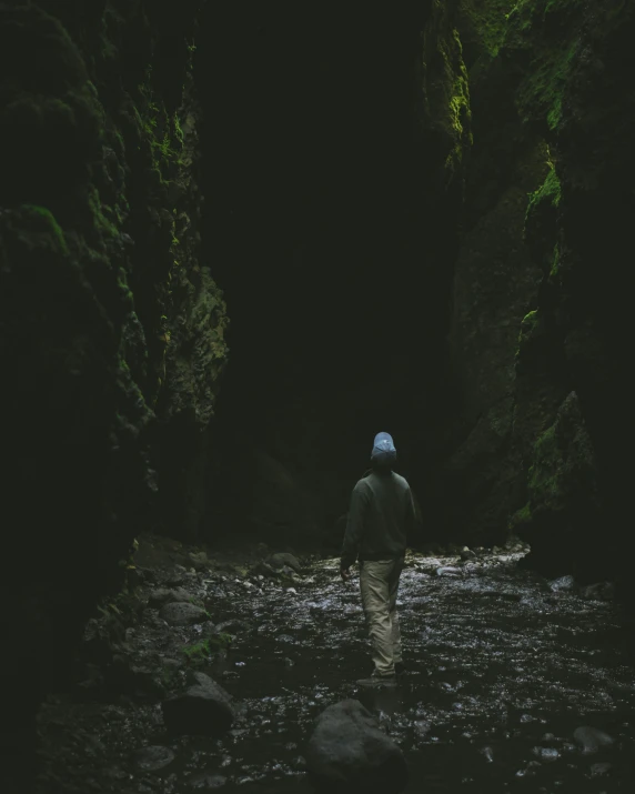 person in the dark walking in a narrow river