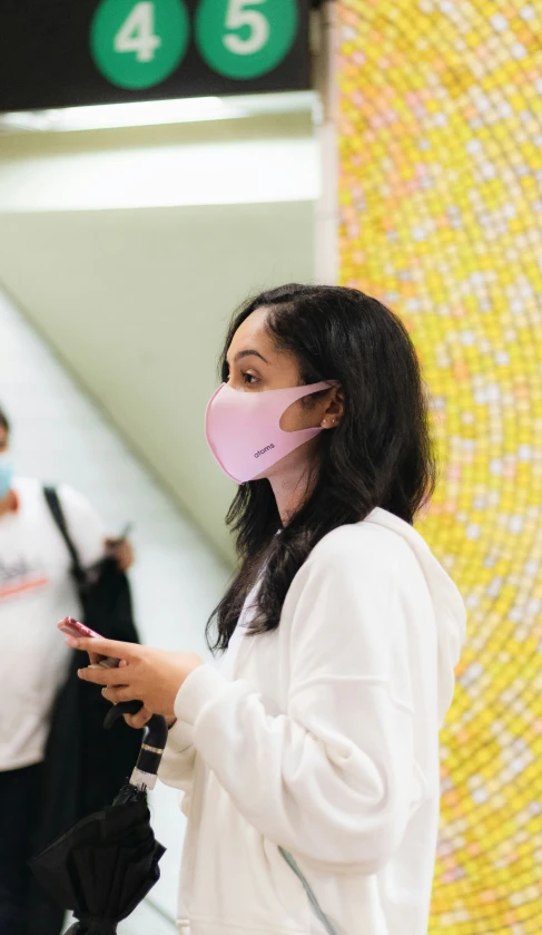 a woman looking at her cell phone wearing a face mask