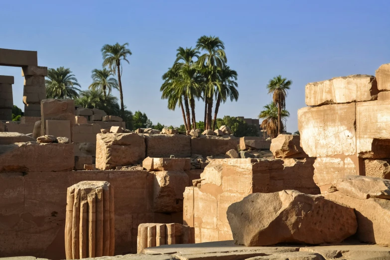 a stone building with carved columns and palm trees behind it