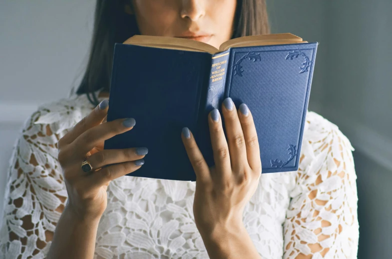 a woman is holding a book in front of her face