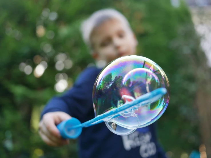 a boy holding soap bubbles in his hand