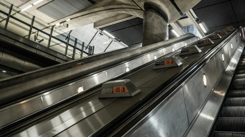 escalator inside an airport with a few signs posted on them