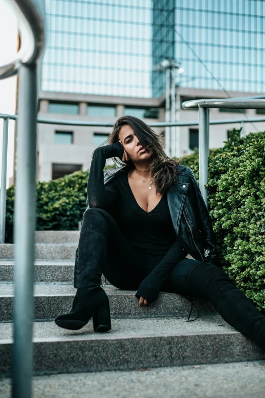 a woman sits on the stairs near some plants and bushes