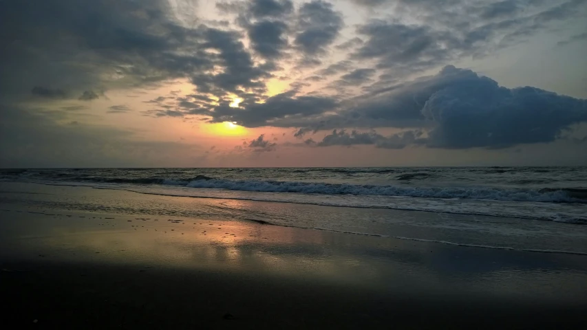 a beach that has some water and clouds on it