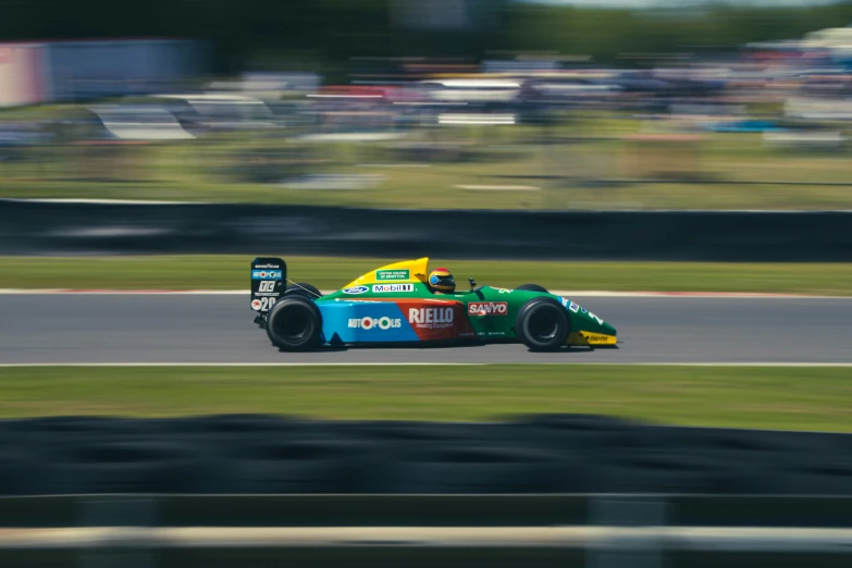 a racing car with some green on it driving through a track