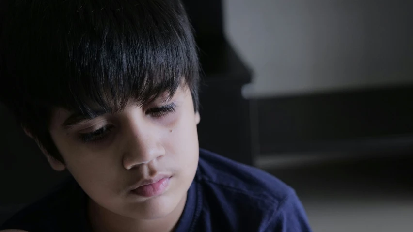 a boy looking down at a piece of food in his hand