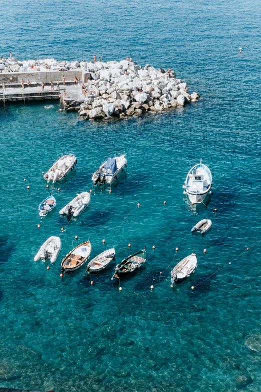 small boats anchored in the water near a pier