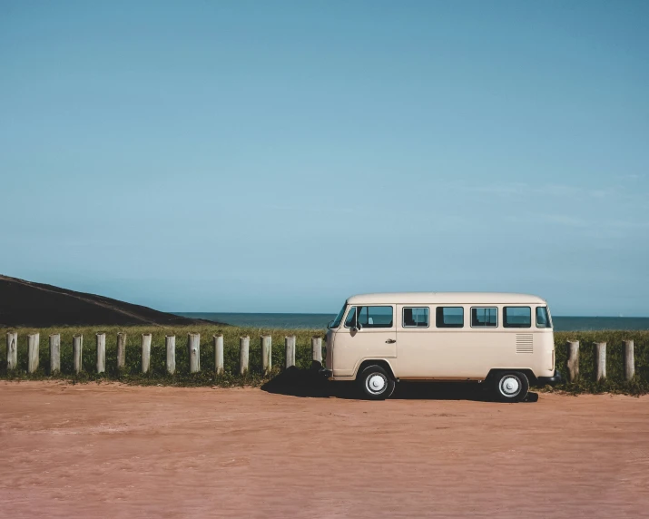 a van is parked on a dirt road next to a fence