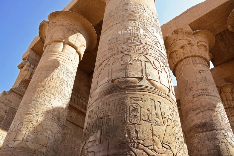 ancient egyptian carved pillars are shown against a blue sky