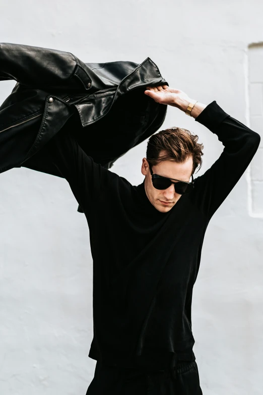 the man wears sunglasses, a black sweater and a black pants