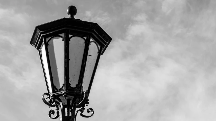 a vintage street light is against a cloudy sky