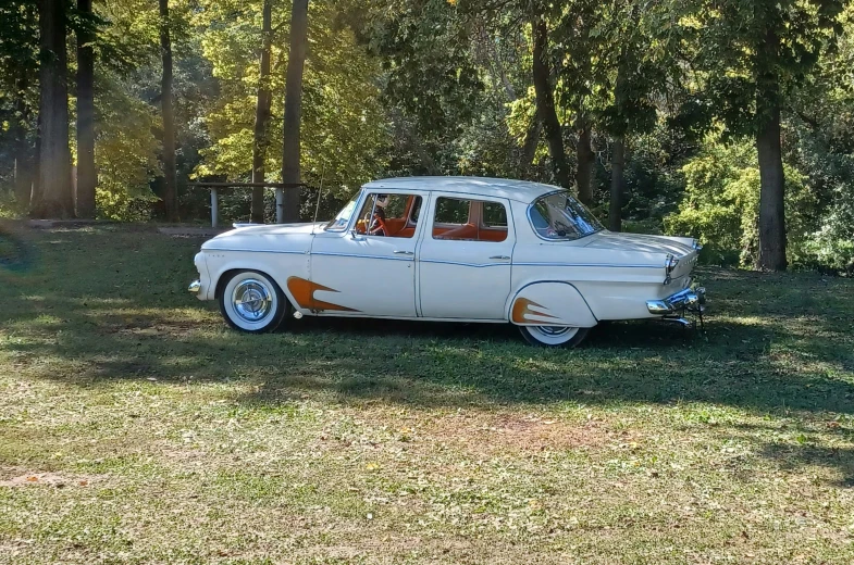 an old fashion white car is parked by trees